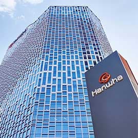 Edificio de la sede de Hanwha en Seúl, con fachada de vidrio y el logotipo de la empresa