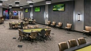 An empty casino poker room with green felt gaming tables and surrounding chairs
