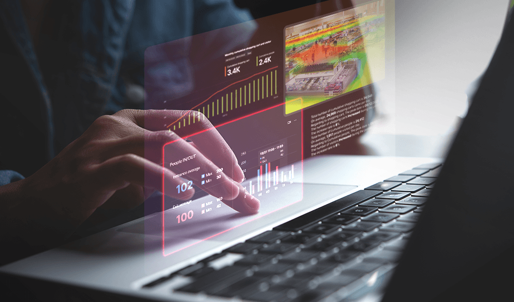 Persona interactuando con un dashboard holográfico de analíticas de video, mostrando mapas de calor, conteo de personas y datos de tráfico de clientes en tiempo real